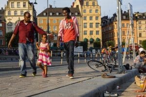 family-walking-Stockholm-harbour-houses-yellow-bikes