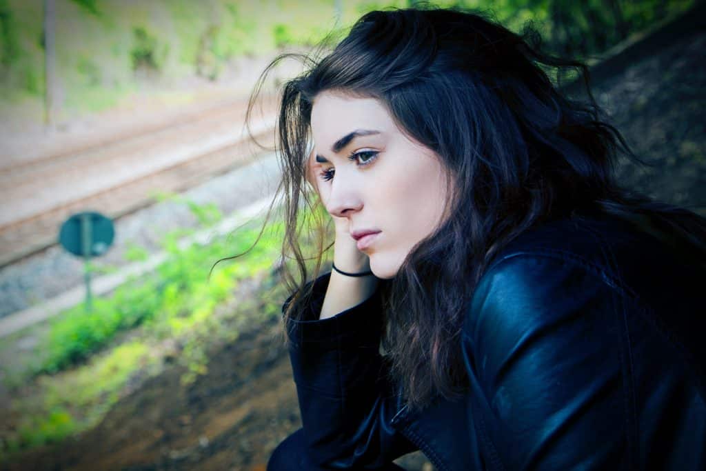 Image of depressed woman looking out of the window and train tracks