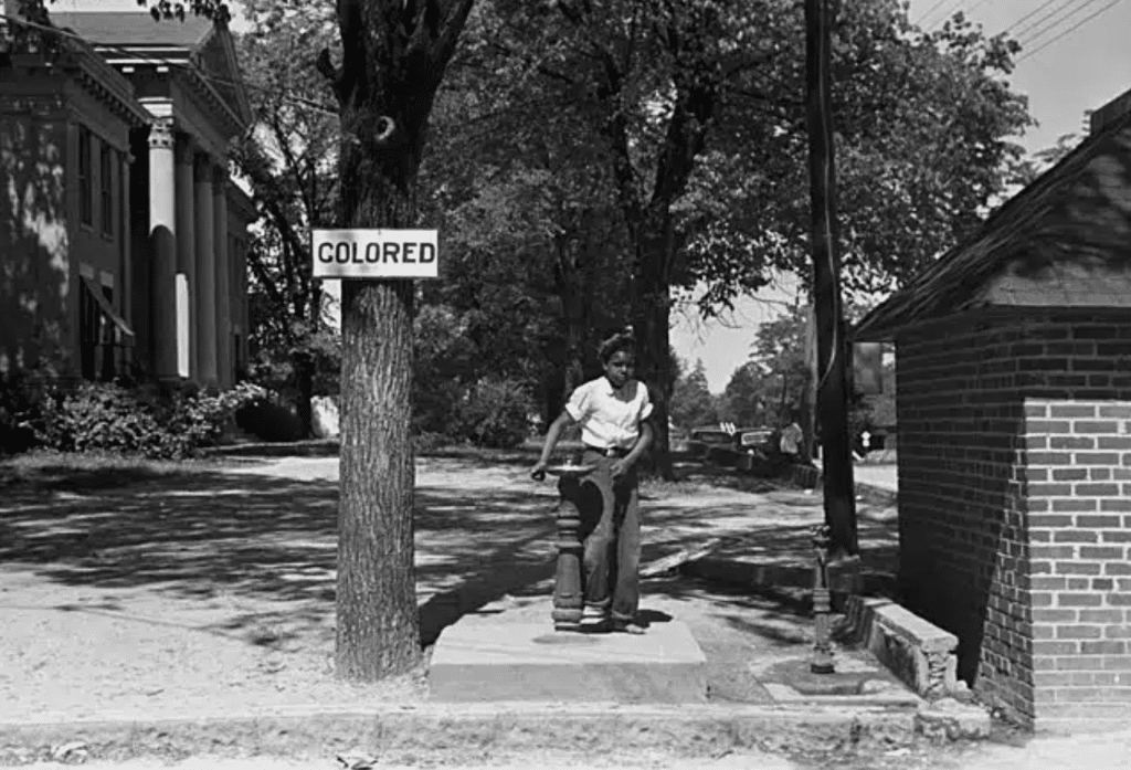 En person drikker fra en brønd, der kun er beregnet til afroamerikanere i North Carolina, USA, i 1938. Billede: John Vachon/Wikimedia