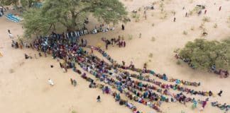 © UNHCR/Colin Delfosse- Menschen, die durch den Konflikt im Sudan vertrieben wurden, stehen bei ihrer Ankunft im Tschad für Hilfe an.
