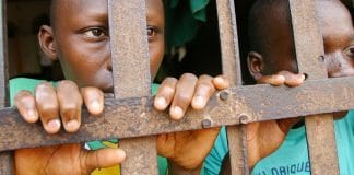 Two young prisoners stand behind bars in a jail in Abomey, Benin.
