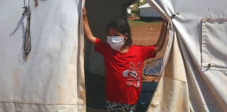 A young girl strands in a tent in a settlement for displaced Syrians in the north of Idlib, in Syria.