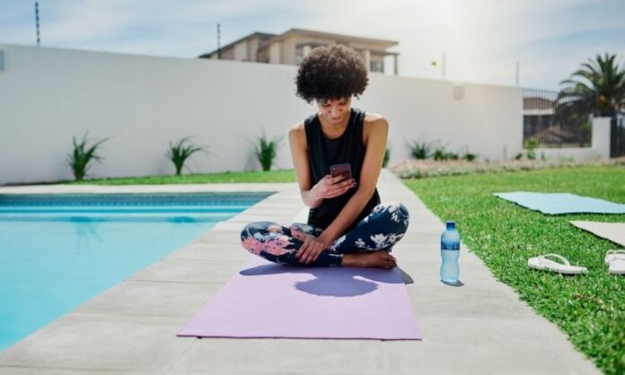Women using mobile app on yoga mat