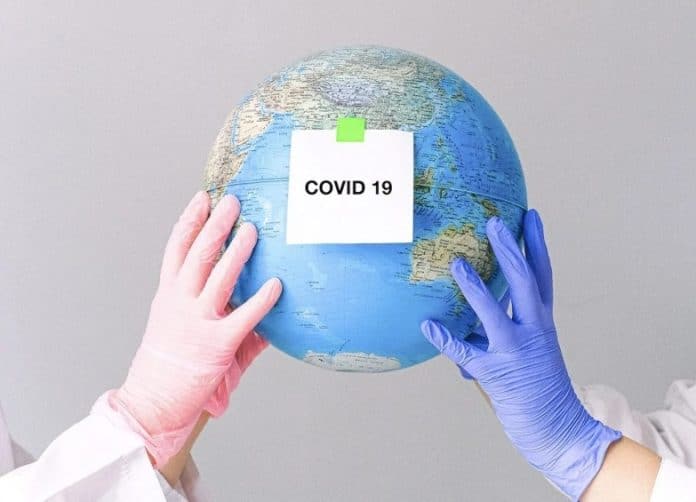 Hands With Latex Gloves Holding a Globe with label 'Covid-19'