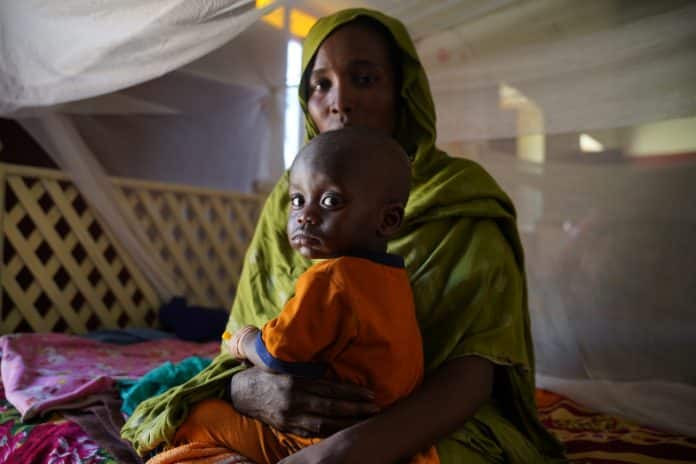 A woman brings her child to a nutrition centre in Abushok, Northern Darfur, Sudan for a health screening © UNICEF/Zakaria