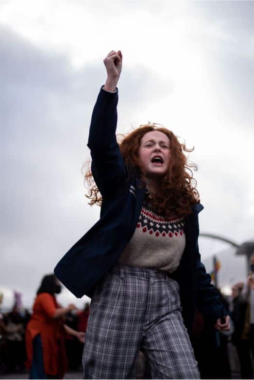 Saoirse Exton protesting on the final day of COP26 with her fist in the air with young protesters in the background
