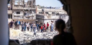 Local people look at damage to a residential community in Gaza.