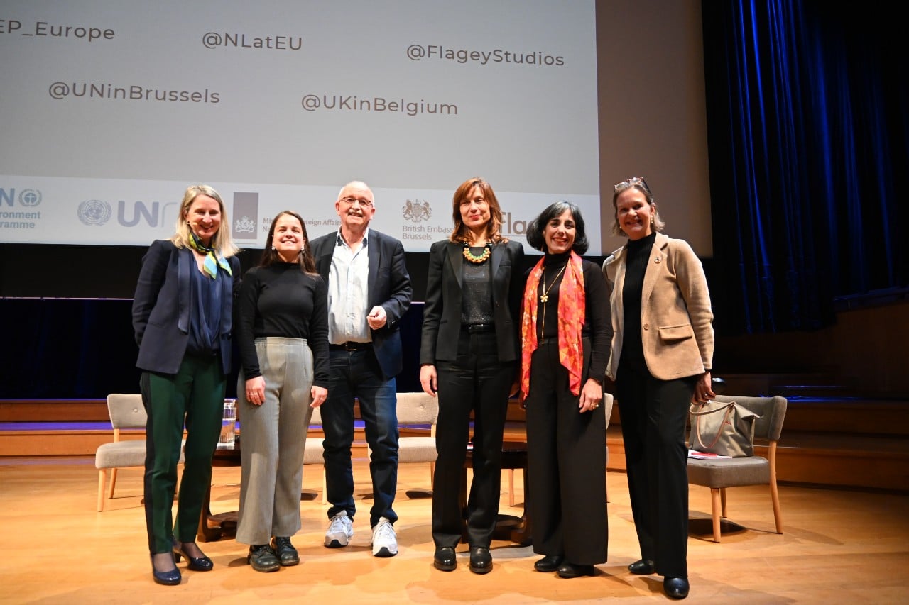 The moderator and panelists pose for a photo on stage with UNRIC Deputy Director Caroline Petit