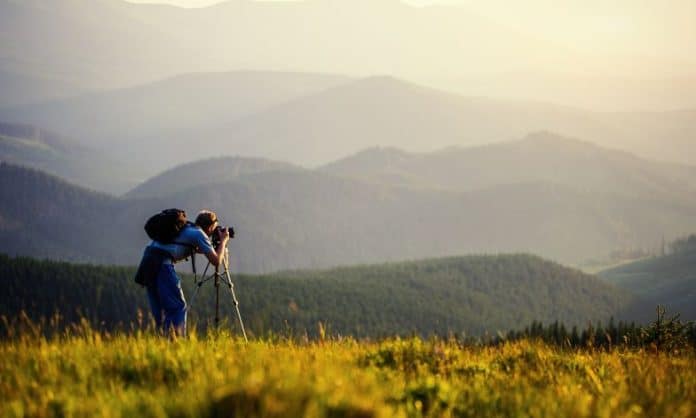 Man taking photographs in hilly landscape