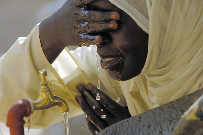 A Sudanese student drinks and washes her face at a new water fountain © UN Photo/Fred Noy