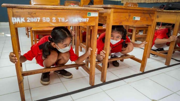 School girls hiding under a table. © UNDRR/Antoine Tardy