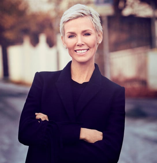 A woman in a black coat smiling to the camera