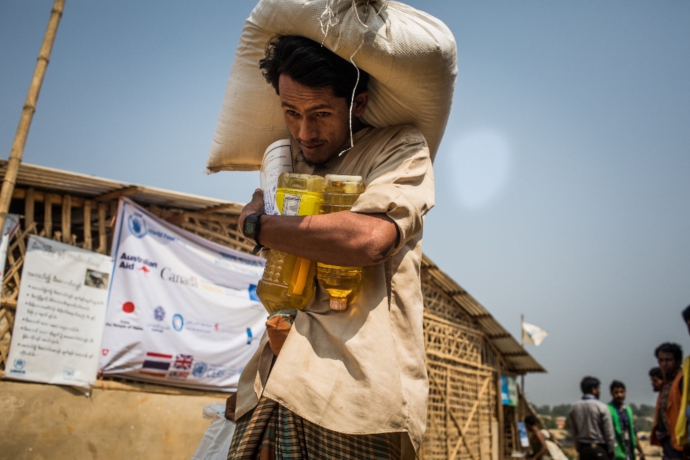A man carrying food supplies in a refugee camp.