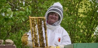 En kvinna i vit dräkt som håller i bin