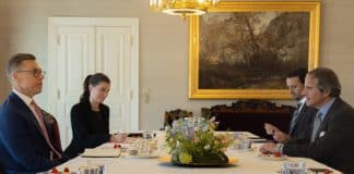 Three men and one woman in formal clothing around a table