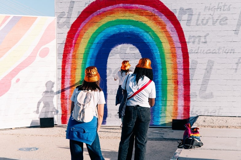 Festival goers in front of a rainbow painted on a wall © Lucas Coelho, Rock in Rio Festival, Lisbon, Portugal