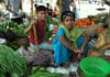Niño y niña sentados en un mercado de de verduras y frutas