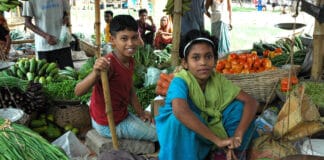 Niño y niña sentados en un mercado de de verduras y frutas