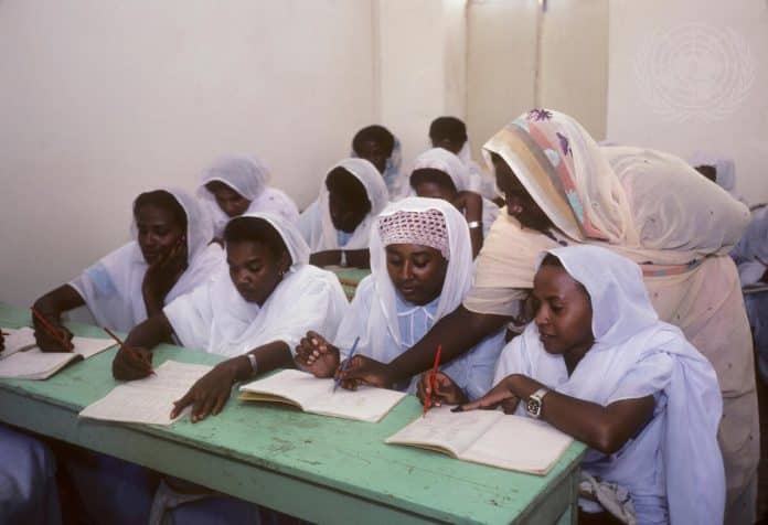 Joukko oppilaita lukevat koulukirjaa koululoukassaan Sudanissa