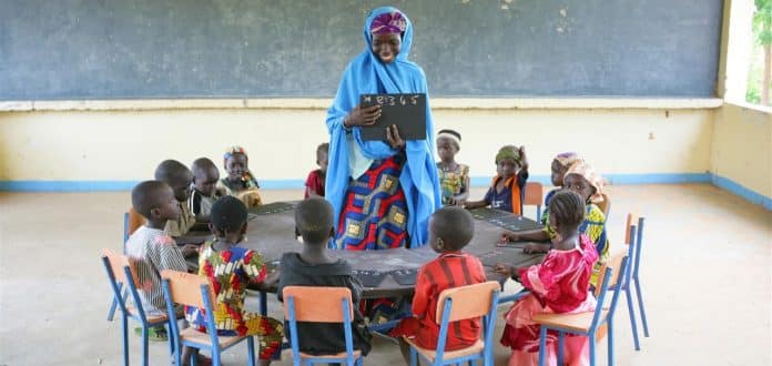 Lapset istuvat opettajansa ympärillään Barin Badjinin kylässä, Nigeriassa