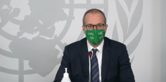 Le Docteur Kluge, directeur de l'OMS Europe, devant un bureau, conférence de presse, portant un masque vert avec l'Objectif de développement durable 3 sur la Santé.