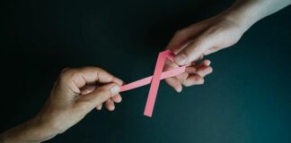 deux mains tiennent un ruban rose contre le cancer