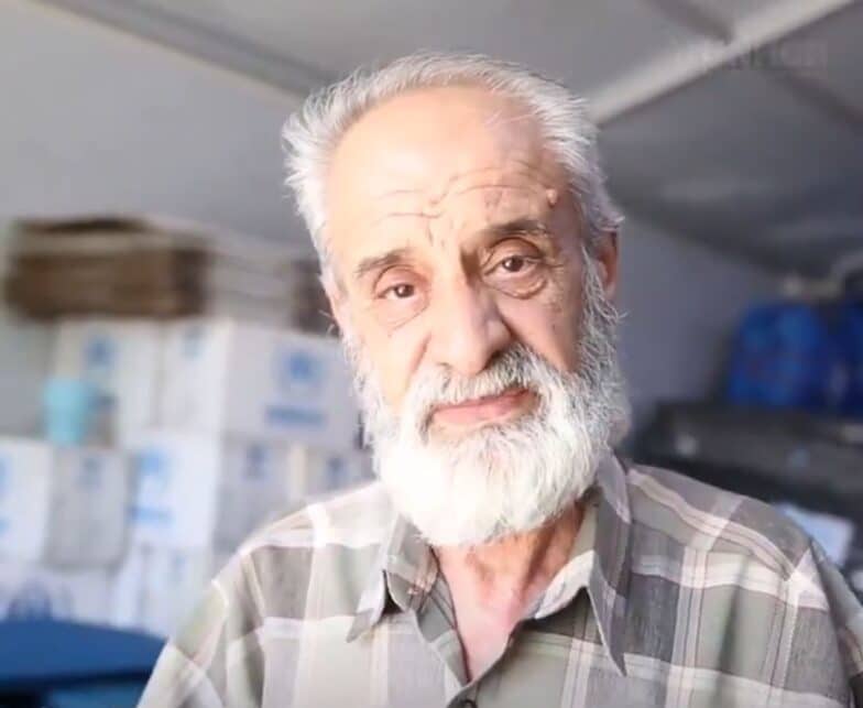 Portrait d'un homme âgé devant des caisses d'aide humanitaire