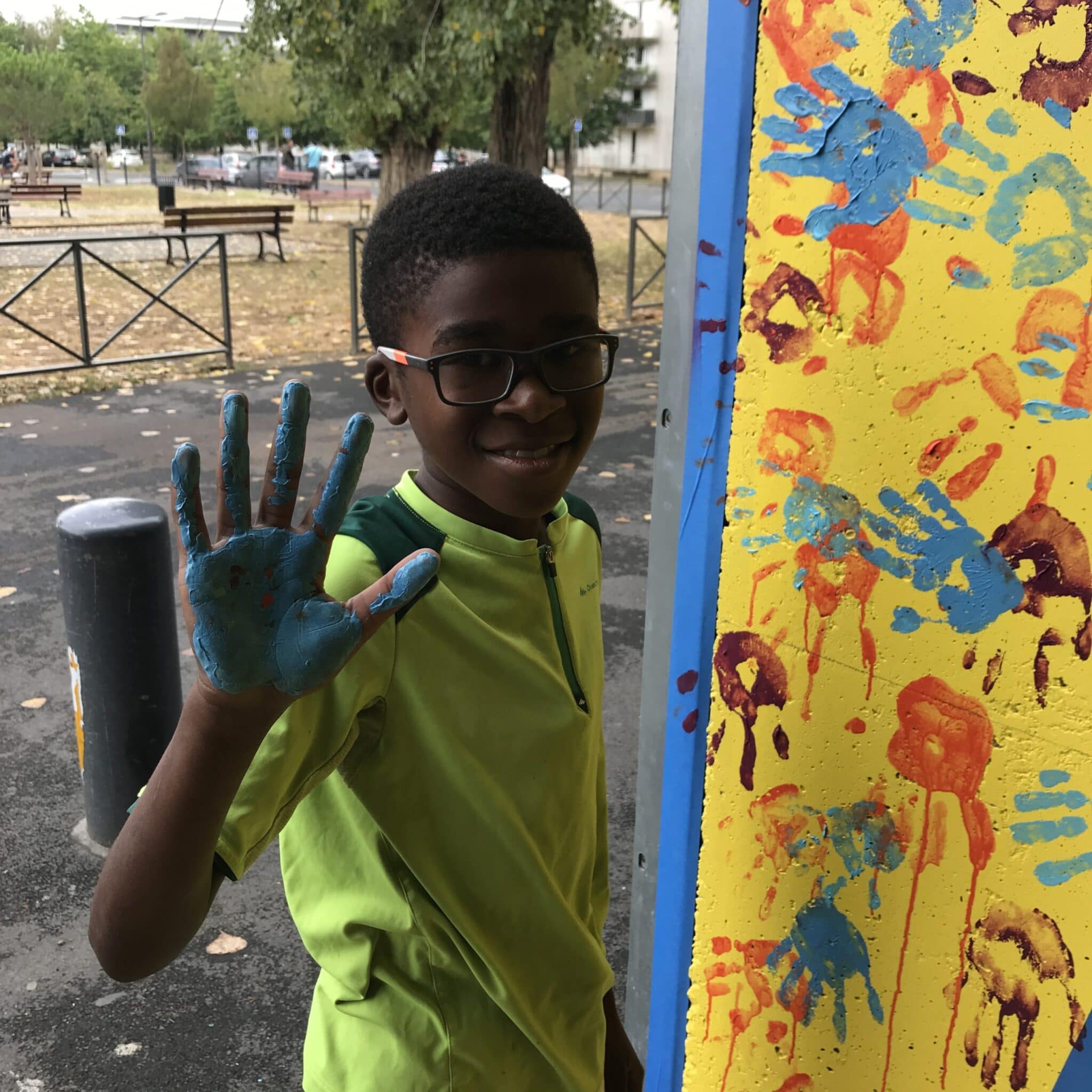 Enfant qui marque son empreinte de la main avec de la peinture sur une fresque murale