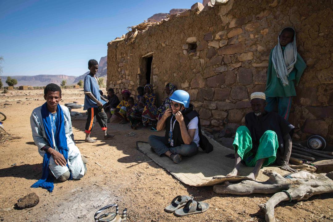 Olivier Salgado assis près d'une maison en pisé entouré de Maliens