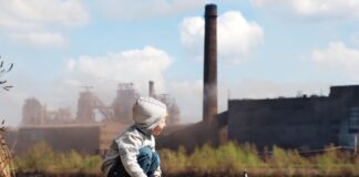 Un enfant jouant dans une zone industrielle contribuant à la pollution de l’air