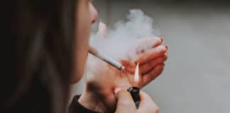 Visage et main d'une fumeuse allumant une cigarette