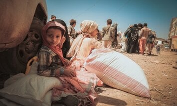 Enfants devant sacs de nourriture dans un camp de déplacés au Yémen