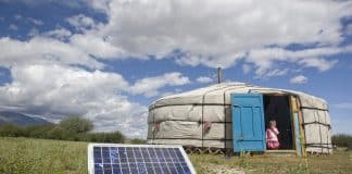 Famille en mongolie devant une tente surmontée d'un panneau solaire, une des sources d'énergies propres
