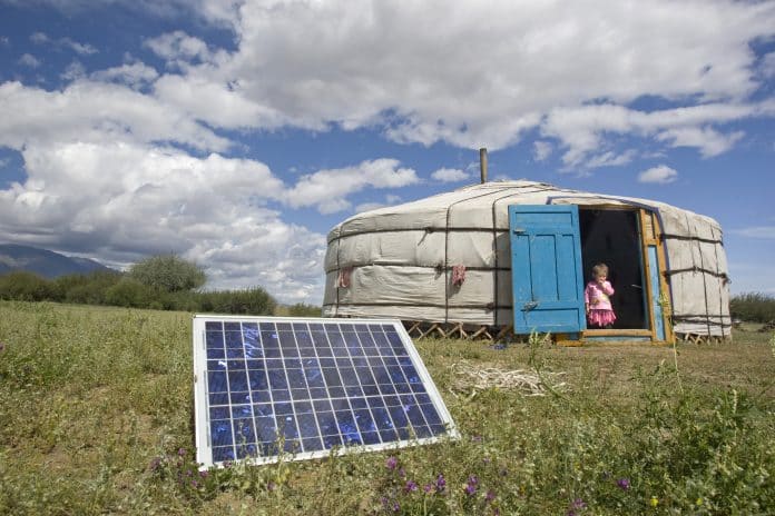 Famille en mongolie devant une tente surmontée d'un panneau solaire, une des sources d'énergies propres