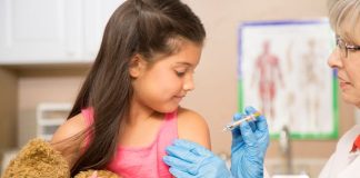 Infirmière qui vaccine une petite fille dans un cabinet médical.