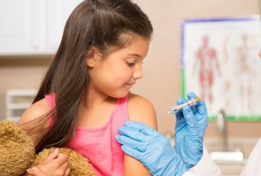 Infirmière qui vaccine une petite fille dans un cabinet médical.