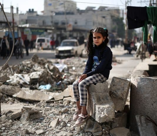 imag d'une enfant devant un batiment détruit. Les armes ne se sont toujours pas tues à Gaza