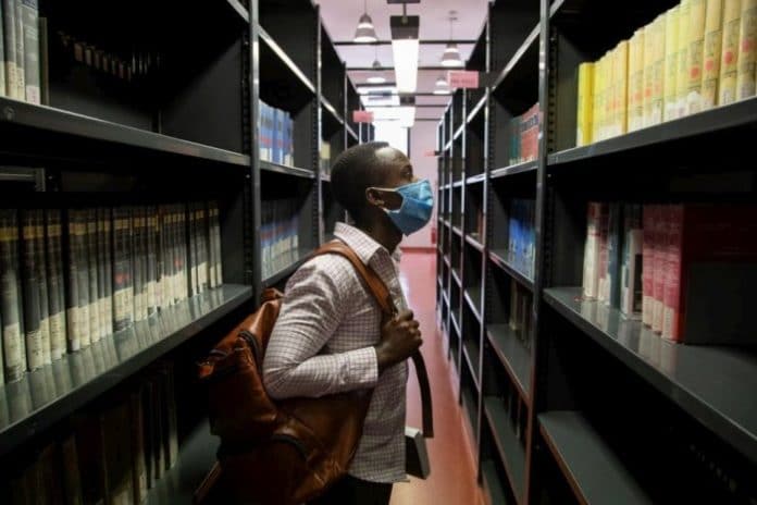 Jules, a 26-year-old student from the Democratic Republic of the Congo, scans the shelves of the social science library at the University of Florence
