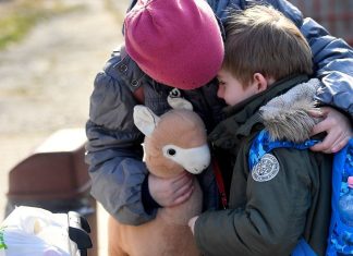 Una bambina ucraina consola suo fratello di sei anni mentre si preparano a lasciare un centro sostenuto dall'UNICEF in Romania per la loro prossima destinazione.