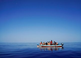 rifugiati e migranti alla deriva in una barca di legno aspettano di essere salvati vicino all'isola italiana di Lampedusa nel Mar Mediterraneo