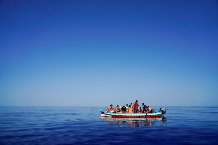 rifugiati e migranti alla deriva in una barca di legno aspettano di essere salvati vicino all'isola italiana di Lampedusa nel Mar Mediterraneo