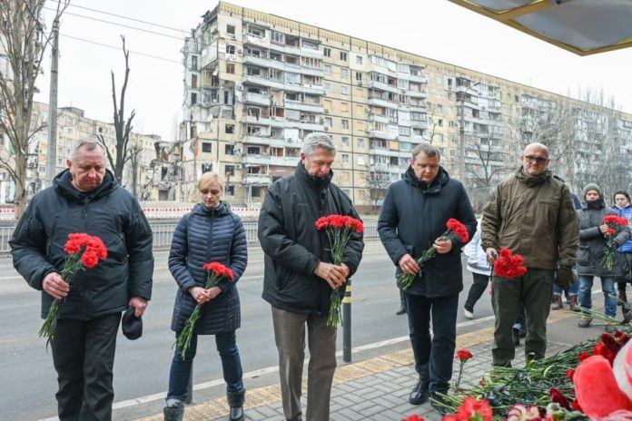 High Commissioner Filippo Grandi (centre), alongside representatives of local authorities, lays flowers at a residential building that was destroyed during a missile strike on 14 January 2023, in Dnipro city, Ukraine