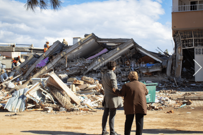 A man and woman look at a collapsed building in Islahyia, Türkiye, on 7 February 2023