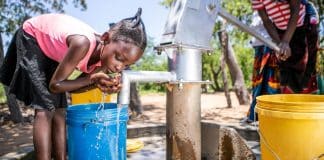 Una giovane ragazza raccoglie dell’acqua da un pozzo