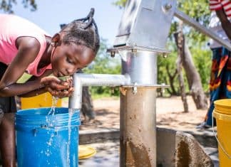 Una giovane ragazza raccoglie dell’acqua da un pozzo