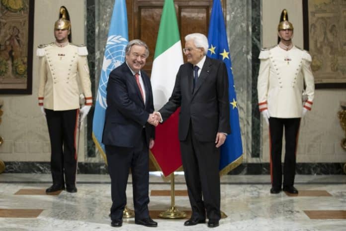 Guterres stringe la mano al Presidente Mattarella davanti alle bandiere dell'ONU, UE e italiana