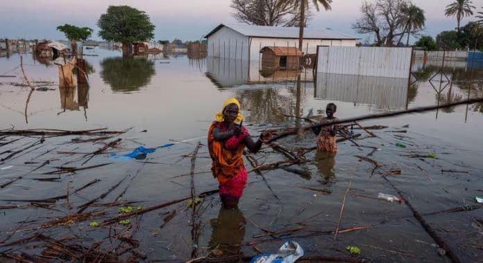 una donna e un bambino sudsudanesi cercano di recuperare i propri averi dopo un alluvione