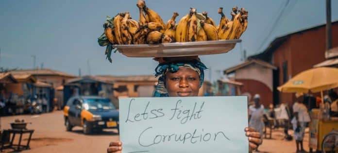 Manifestante in Ghana mostra cartello contro la corruzione