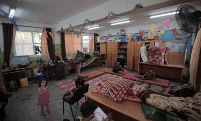 Una famiglia si riunisce in un'aula della New Gaza Boys School dell'UNRWA, nella Striscia di Gaza. Quasi 74.000 sfollati si trovano ora in 64 rifugi dell'UNRWA.