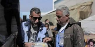 Mahmoud (a destra) esamina un pacco di cibo in un magazzino dell'UNRWA.